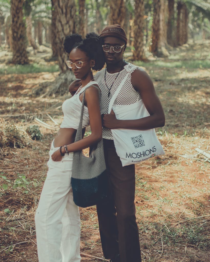 Fashionable couple posing amidst palm trees, showcasing trendy summer style.