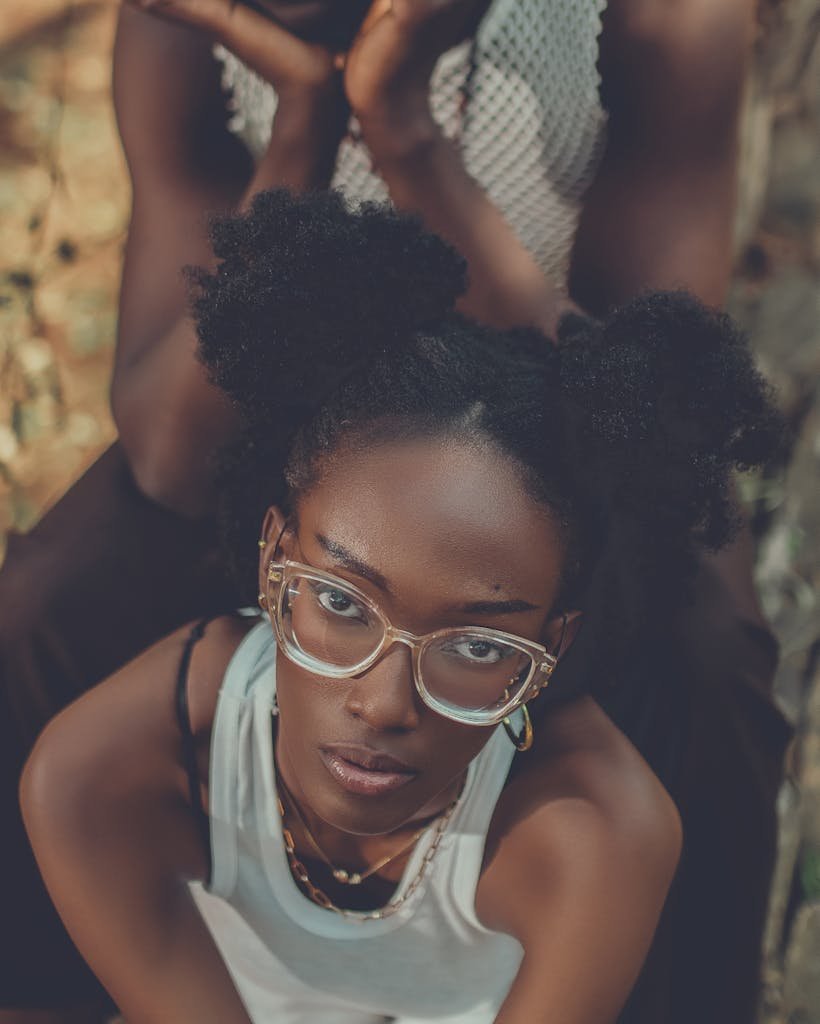 Stylish young woman with glasses and natural hair posing outdoors. Fashionable expression.